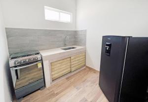 a kitchen with a black refrigerator and a sink at Comunidad Calle 13 Hotel Boutique in Santa Marta