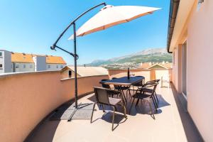 a balcony with a table and chairs and an umbrella at Apartment Hilda in Solin