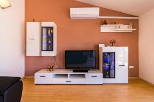 a living room with a tv and a white entertainment center at Apartment Hilda in Solin