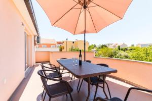 a table and chairs on a balcony with an umbrella at Apartment Hilda in Solin