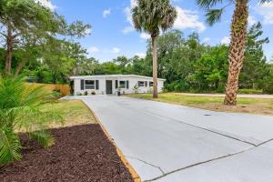 a house with a palm tree and a driveway at Cabana Isla- Hot Tub- Boat RV- Mins to DT & Beach in St. Augustine