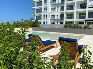 two chairs and a swimming pool in front of a building at Apartamento con piscina privada Morros Io in Cartagena de Indias