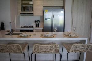 a kitchen with a counter with chairs and a refrigerator at Apartamento con piscina privada Morros Io in Cartagena de Indias