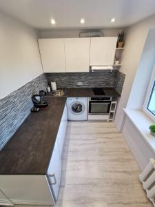 a kitchen with white cabinets and a washer and dryer at Home 4 YOU - self check-in in Ventspils