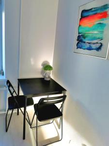 une table noire et une chaise dans une pièce avec un tableau dans l'établissement Home 4 YOU - self check-in, à Ventspils