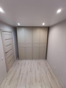 an empty room with white cabinets and wood floors at Home 4 YOU - self check-in in Ventspils