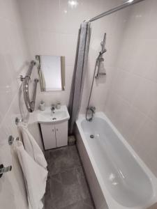 La salle de bains blanche est pourvue d'un lavabo et d'une baignoire. dans l'établissement Home 4 YOU - self check-in, à Ventspils