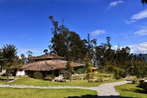 a house with a straw roof and a gravel path at Allpa Wasi - Casa Suaya La Esperanza in Ibarra