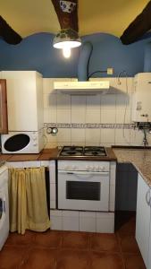 a kitchen with a white stove top oven next to a microwave at Casa Rural Obrador. in Montoro de Mezquita