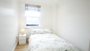 London Apartments 4U في لندن: غرفة نوم بيضاء بها سرير ونافذة