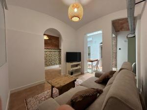 Una sala de estar con un sofá y un televisor. en Atocha Boutique Badajoz, en Badajoz