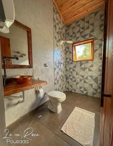 a bathroom with a toilet and a sink and a mirror at Pousada La na Roça in Paraisópolis