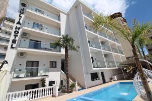an apartment building with a swimming pool and palm trees at Julia Hotel in Sarandë