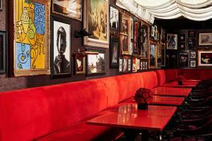 a restaurant with red tables and pictures on the wall at The Vagabond Club A Tribute Portfolio Hotel Singapore in Singapore