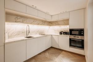uma cozinha branca com armários e electrodomésticos brancos em HIGHSTAY - Luxury Serviced Apartments - Place Vendôme em Paris