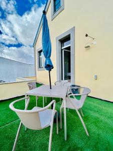 een patio met een tafel en stoelen en een parasol bij Plaza House Ílhavo in Ílhavo
