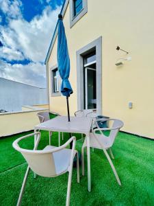 a patio with a table and chairs and an umbrella at Plaza House Ílhavo in Ílhavo