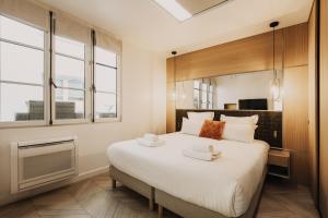 um quarto com uma grande cama branca e janelas em HIGHSTAY - Luxury Serviced Apartments - Place Vendôme em Paris