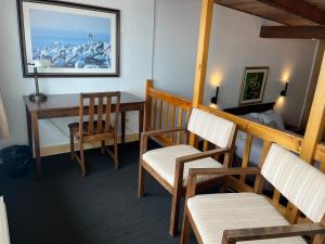 Zimmer mit Stühlen, einem Schreibtisch und einem Tisch in der Unterkunft Hôtel La Côte Surprise in Perce