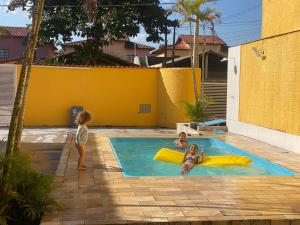 two children are playing in a swimming pool at POUSADA AMARELA in Itanhaém