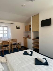 1 Schlafzimmer mit 2 Betten, einem Tisch und einer Küche in der Unterkunft Penzion, vinný sklep a café Bárta in Mikulov