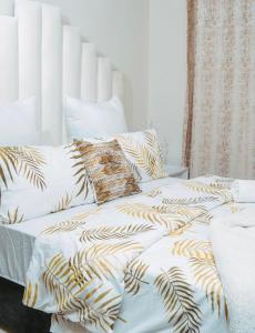 Sunset Gold-2 Bedrooms Apartment في Fourways: غرفة نوم بسريرين بيض و جولدن