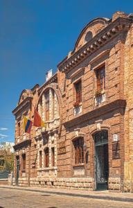 a large brick building with flags on it at Hotel Victoria in Cuenca