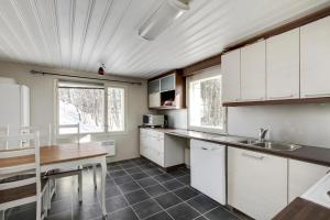 uma cozinha com armários brancos e uma mesa de madeira em Cozy cottage in Pontus em Lappeenranta