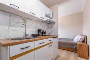 een keuken met witte kasten, een wastafel en een bed bij Luna solari Apartment in Mantoúkion