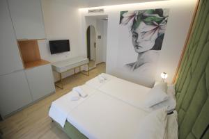 a room with a bed and a painting of a woman at Julia Hotel in Sarandë