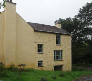 an old yellow building with windows on a field at Ynyswen bed & breakfast in Nantgaredig