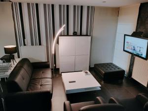 a living room with a couch and a tv at In Het Spoor Van De Vos in Zutendaal