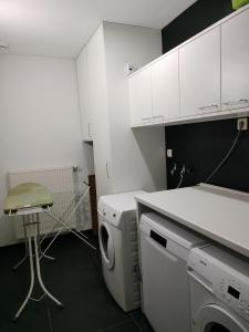 a white kitchen with a washing machine and a stool at In Het Spoor Van De Vos in Zutendaal