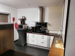 a kitchen with white cabinets and black appliances at In Het Spoor Van De Vos in Zutendaal