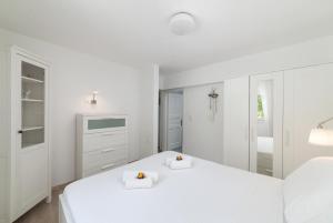 a white bedroom with two beds and a mirror at Cozy Cottage in Istron