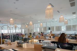 a restaurant with people sitting at tables and chandeliers at Selina Kinneret in Migdal