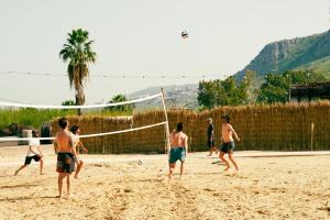 a group of men playing a game of volleyball on a beach at Selina Kinneret in Migdal