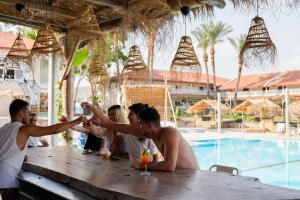 a group of people sitting at a table near a pool at Selina Kinneret in Migdal