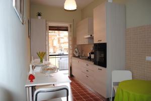 une cuisine avec des placards blancs et une table verte dans l'établissement B&B Di Leo, à Rome