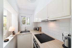 a white kitchen with a sink and a counter at Cozy Cottage in Istron