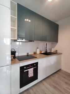 a kitchen with white cabinets and a black stove top oven at Nowoczesny apartament dla par in Kraków