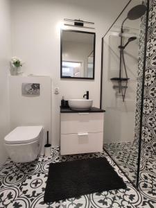 W łazience znajduje się umywalka, toaleta i lustro. w obiekcie Nowoczesny apartament dla par w Krakowie