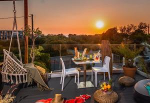 einen Balkon mit einem Tisch und Stühlen sowie einem Sonnenuntergang in der Unterkunft Antonakis Villa, Near Beach, Private Pool in Kremasti