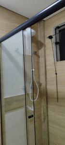 a glass shower stall with a white hose at Sevili Garden Hotel in Arujá
