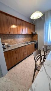a kitchen with wooden cabinets and a table and chairs at Super House Blloku - 3 Rooms in Tirana