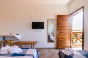 Cette chambre comprend deux lits, une table et une télévision. dans l'établissement Vila Bella Barra Grande, à Barra Grande