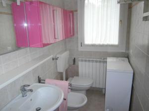 La salle de bains est pourvue de toilettes, d'un lavabo et de placards roses. dans l'établissement Casa Incanto - Agenzia Cocal, à Caorle