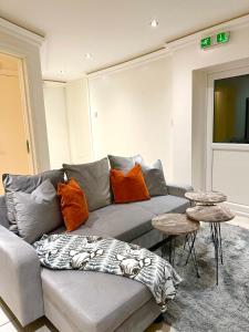 a living room with a gray couch with orange pillows at Stylish 3-Bedroom Flat in Prime Location in London