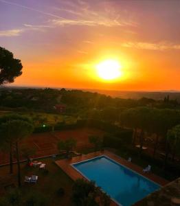 a sunset over a swimming pool with the sun setting at Residence La Villa in Montescudaio