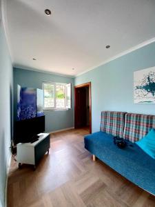uma sala de estar com um sofá azul e uma televisão de ecrã plano em Casa do Portão Azul - Salmonete em Atouguia da Baleia